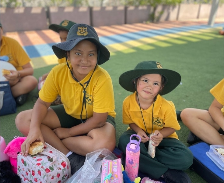 Two students sitting on the grass enjoying their lunch.