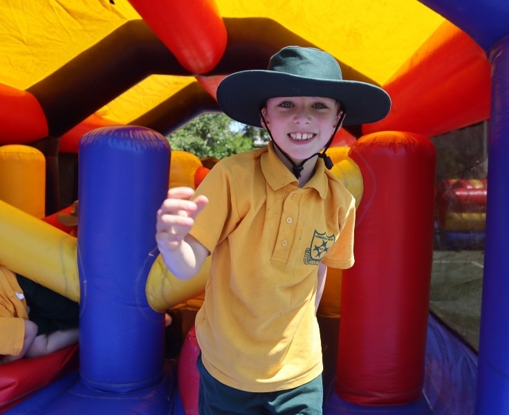 Student smiling while playing inside a colourful inflatable obstacle course.