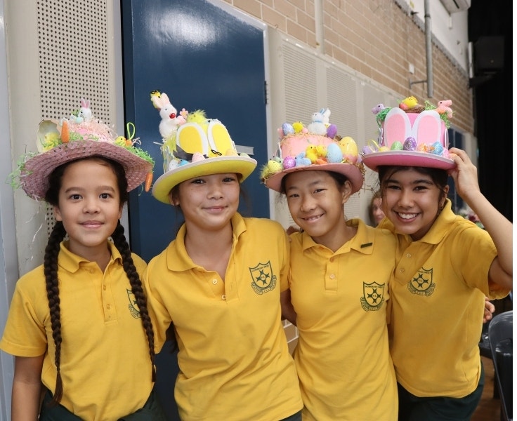 Students smiling and wearing decorated Easter hats.
