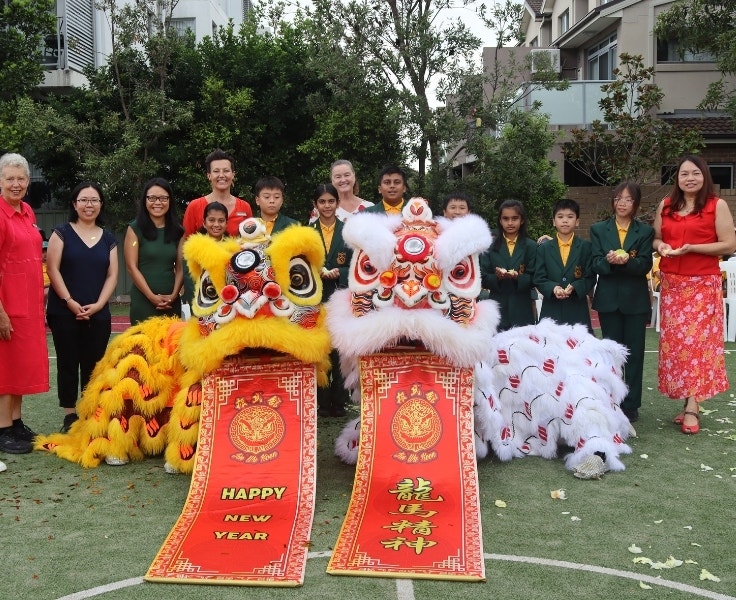 Students and staff posing with lion dance performers for a Lunar New Year celebration.