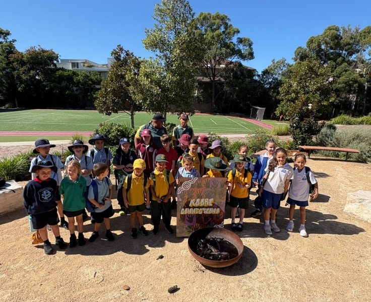 Students standing outdoors around a yarning circle before a cultural activity.