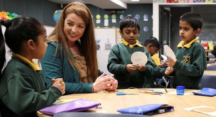 Teacher supporting students during a classroom craft activity.