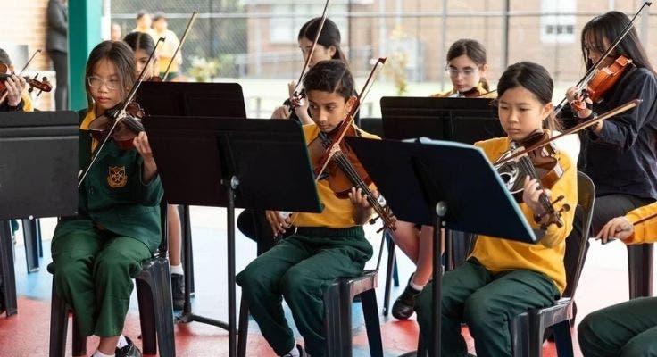 Students playing violins during a music ensemble.